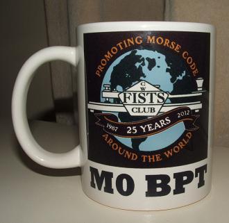 Photograph of the FISTS 25th Anniversary Mug with the black version of the anniversary logo and M0BPT printed underneath it