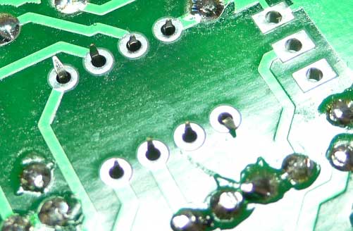 Photograph of bottom of PCB showing two corner IC socket pins bent to hold it in place